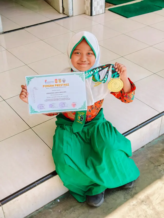 Siswi MI Al Ahmad menunjukkan medali dan piagam Juara 1 Kumite karate